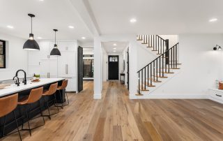 Kitchen and living room interior in new farmhouse style luxury home with open concept floor plan. Features large island with farmhouse sink, hardwood floors, and black accents. how long does interior paint take to dry