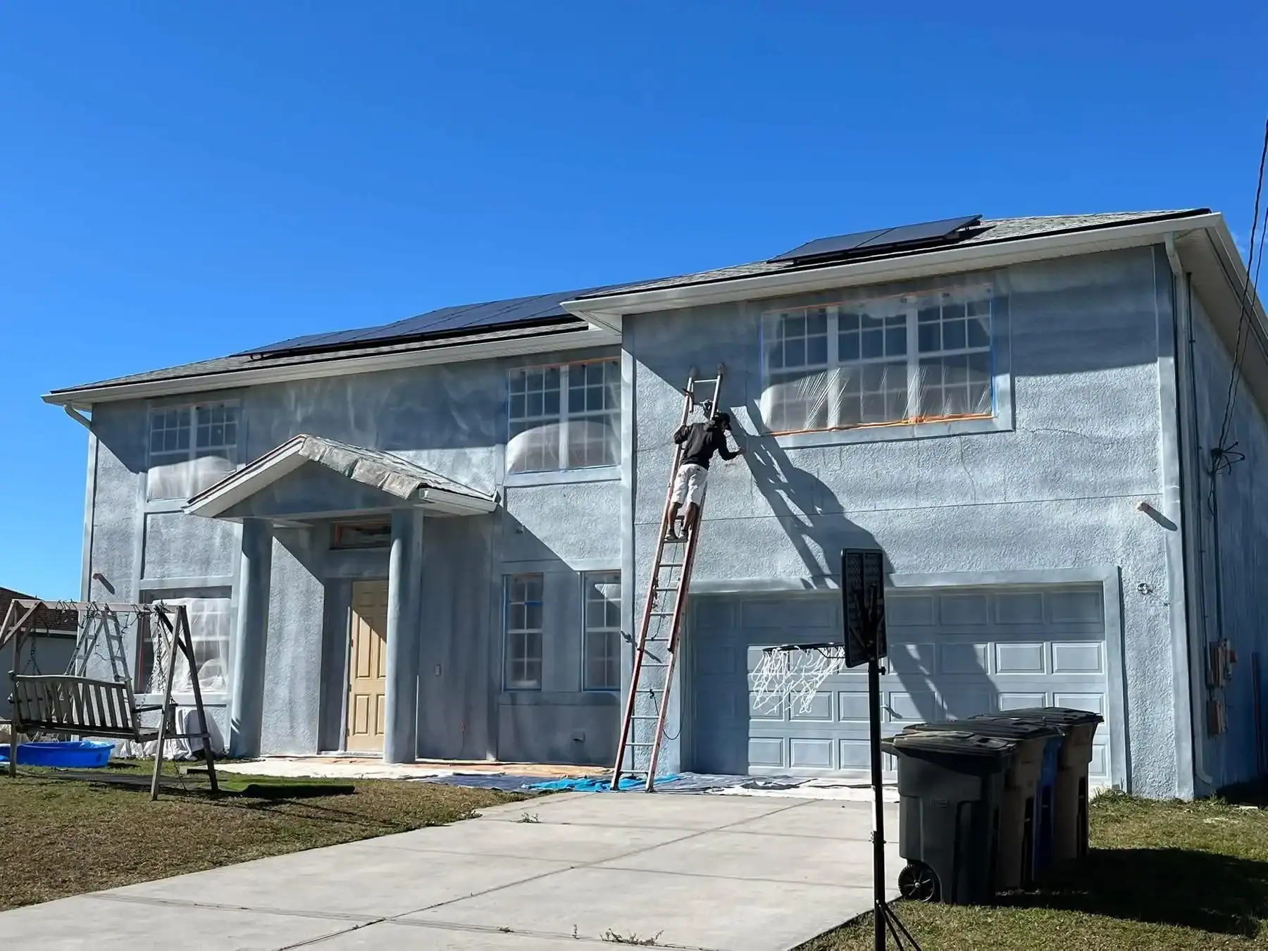 Professional Exterior House Painting in Southwest Florida Painter on a ladder applying fresh paint to a residential home exterior in Southwest Florida.
