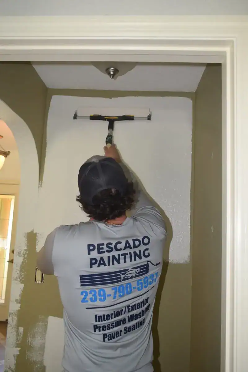 Professional Interior Wall Painting Services in Southwest Florida A skilled painter applying fresh white paint to an interior wall in a Southwest Florida home.