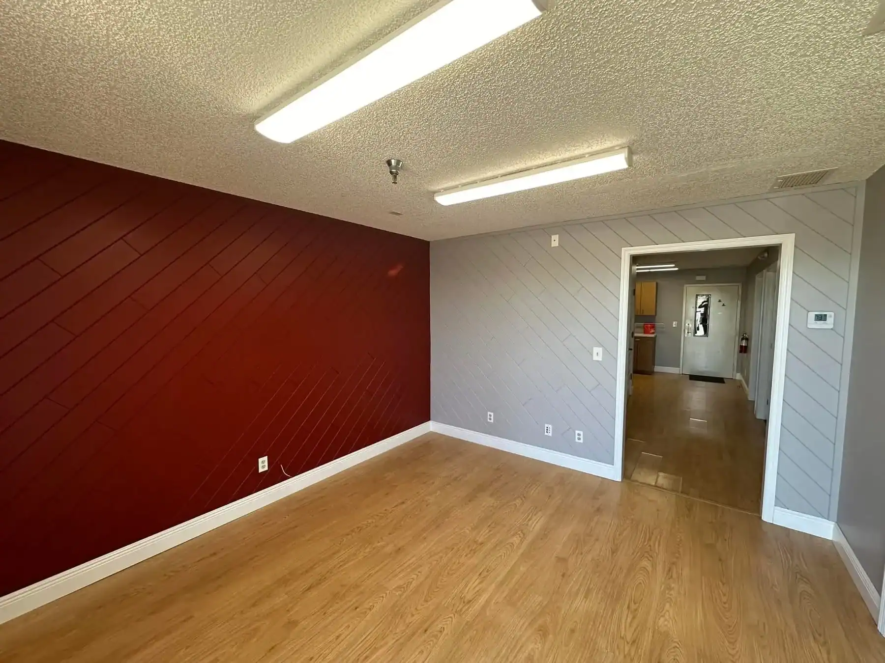Accent Wall and Texture Painting for Commercial Spaces Southwest Florida Interior room with a bold red accent wall and gray textured walls, featuring wood laminate flooring in Southwest Florida.