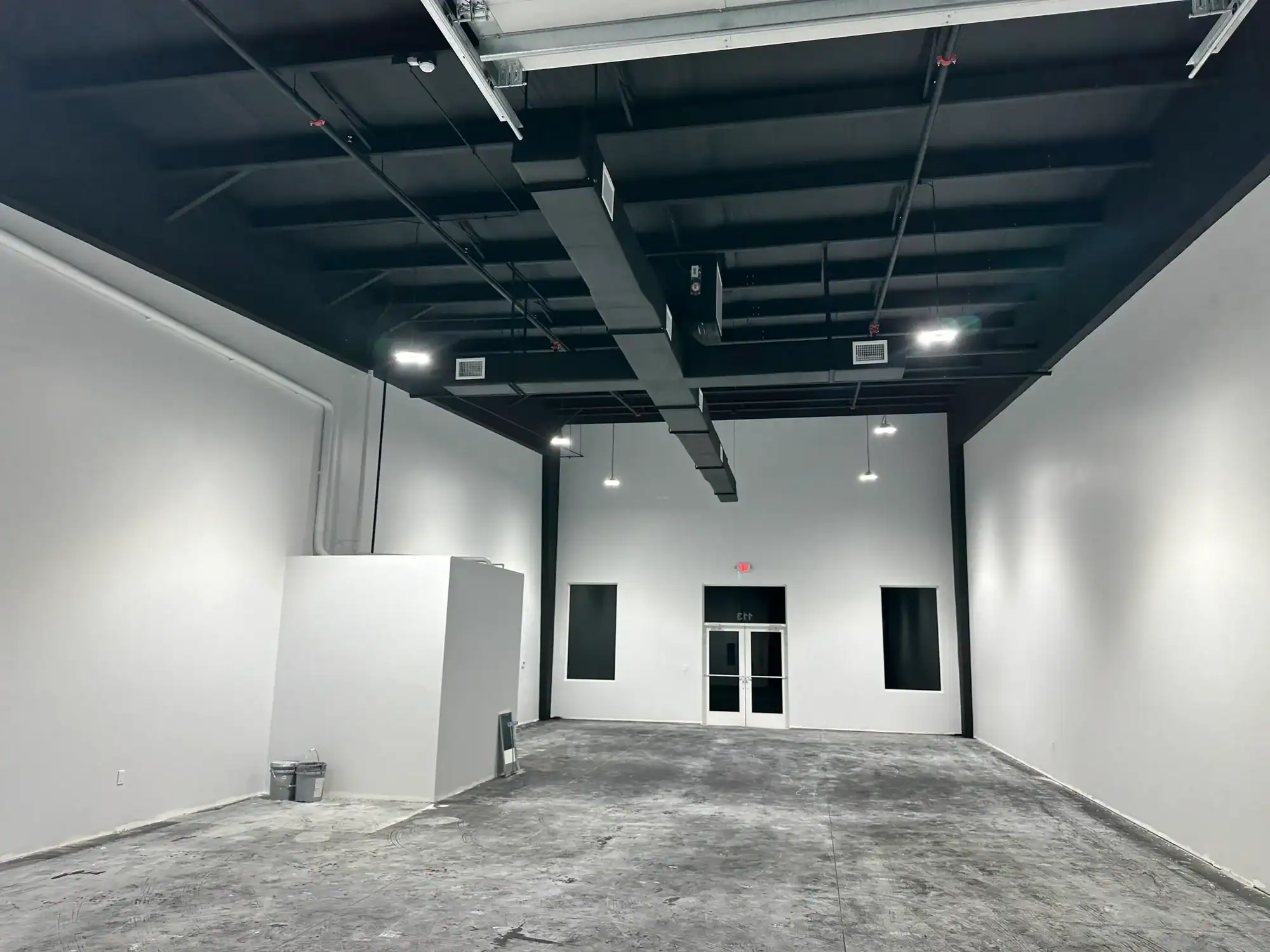 Commercial Interior Painting for New Construction Southwest Florida Large empty commercial space with freshly painted white walls and a black ceiling with exposed ducts in Southwest Florida.