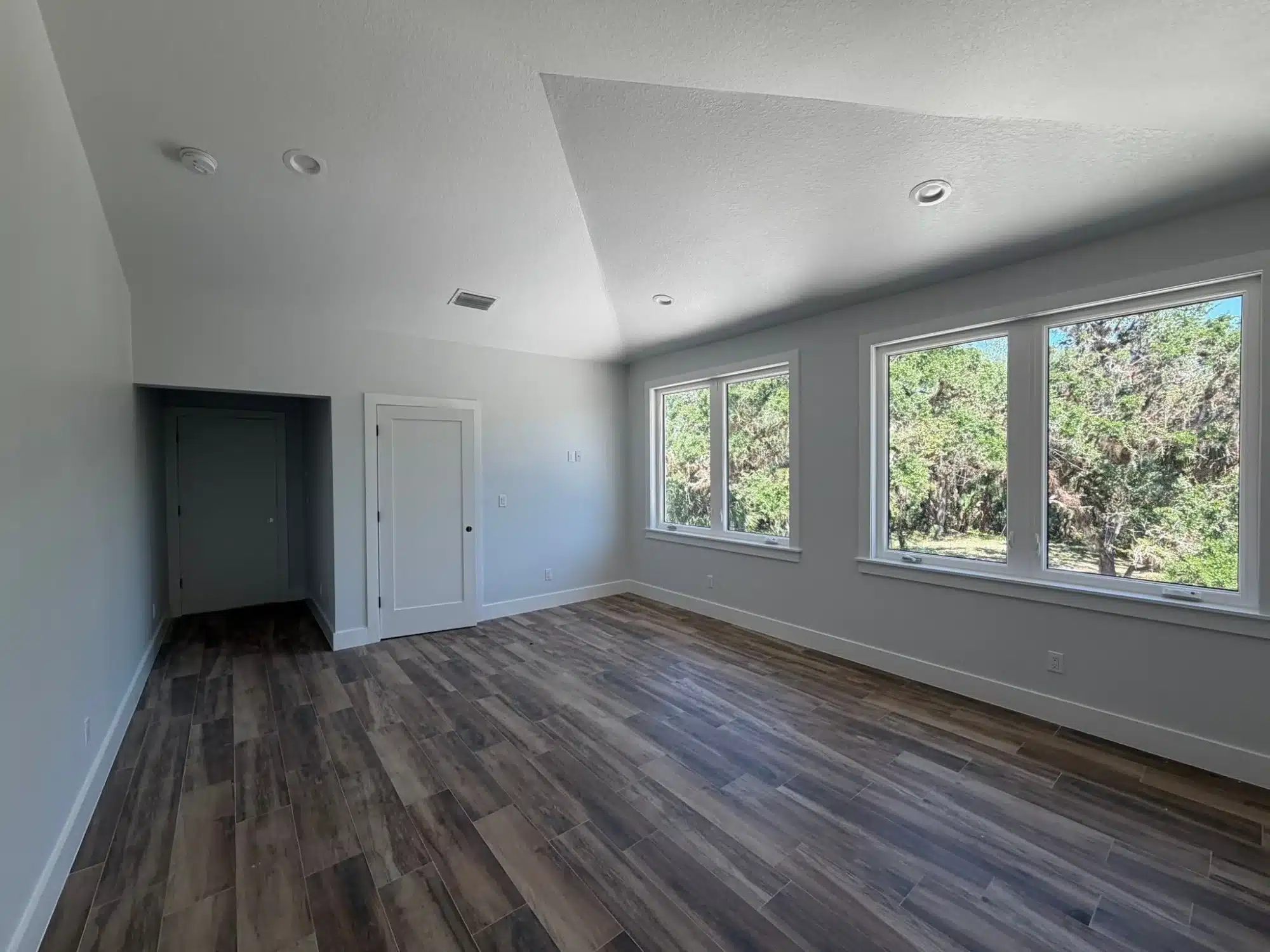 Interior Residential Painting Cape Coral Light gray painted walls and white ceiling in residential room with dark wood flooring and large windows