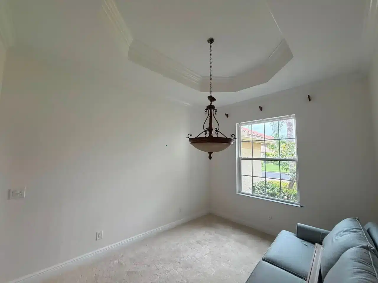 Off-White Tray Ceiling Room Off-white painted walls and tray ceiling with decorative molding in residential room with large window and pendant fixture