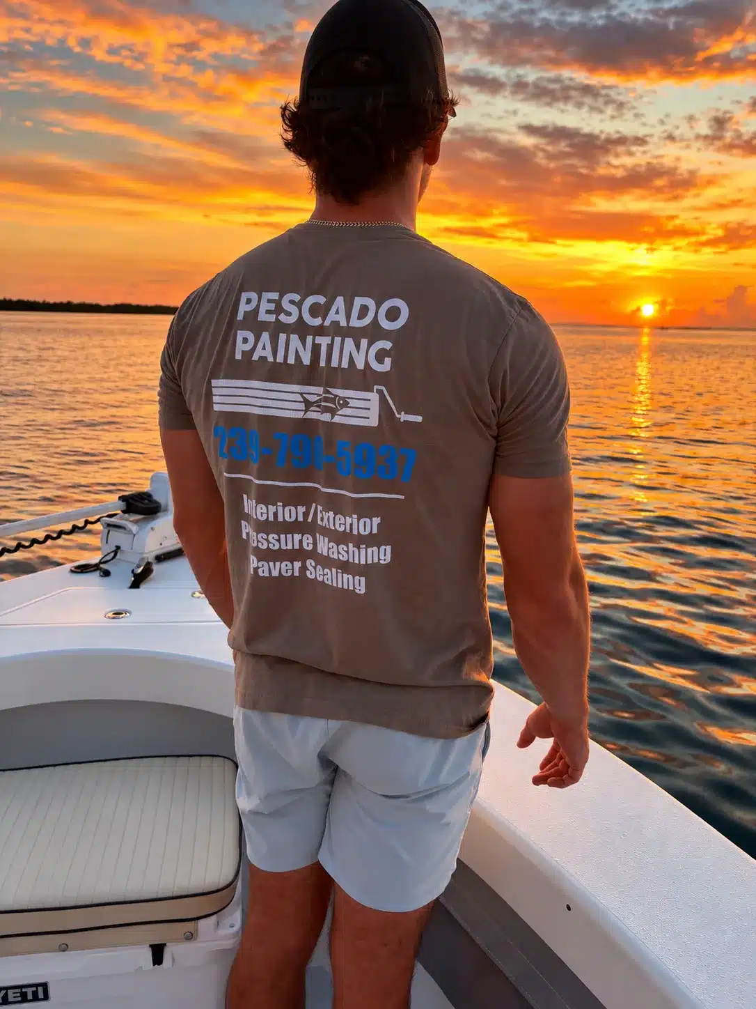 Pescado Painting Company T-Shirt Man wearing gray Pescado Painting branded t-shirt on boat at sunset